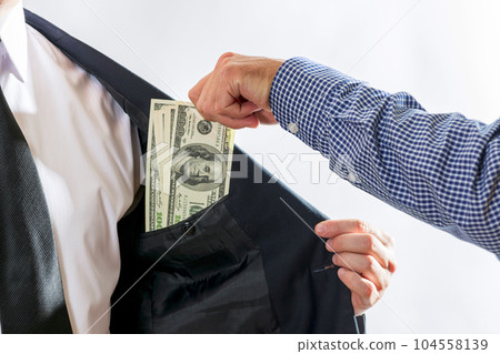Businessman in a suit takes dollar bills in his pocket as a bribe Businessman in a suit takes dollar bills in his pocket as a bribe 104558139