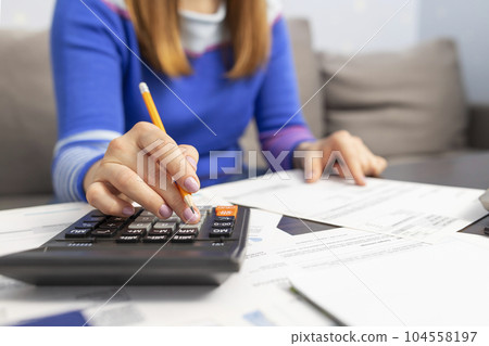 Woman using calculator for calculate domestic bills at home, doing paperwork 104558197