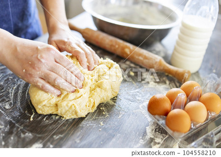 Female hands making dough for baking on wooden table 104558210