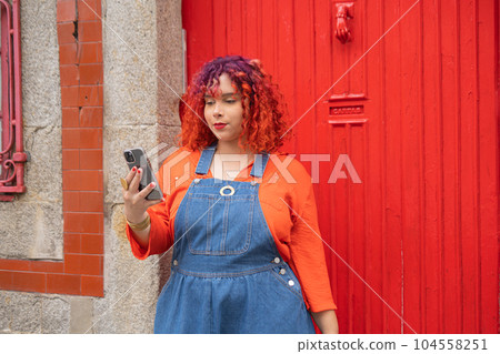 Young Femele holding smartphone against red door 104558251