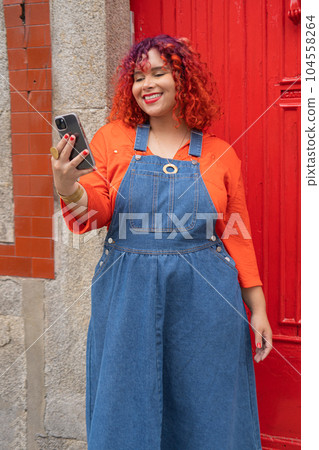 Young Femele holding smartphone against red door 104558264