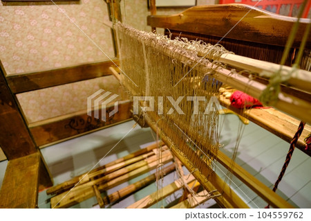 Old wooden loom. A loom made in the 19th century. The interior of a craftsman's house in the last century. Kihnu Island in Estonia Old wooden loom. A loom made in the 19th century. The interior of a craftsman's house in the last century. Kihnu Island in Estonia 104559762