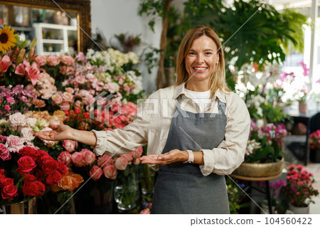 Smiling woman florist small business owner standing in own floral store and waiting for client 104560422