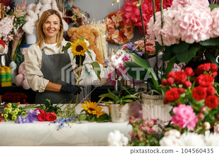 Professional florist in flower shop make bouquet for holiday and looking at camera 104560435