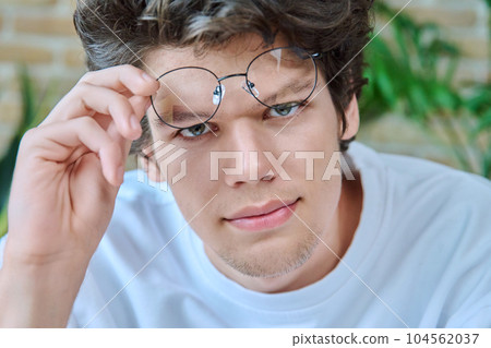 Close-up face of young handsome guy wearing glasses looking at camera 104562037