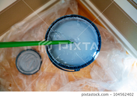 Stirring gray paint in a bucket for high-quality wall painting Stirring gray paint in a bucket for high-quality wall painting 104562402