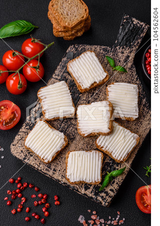 Delicious salty rectangular wheat croutons with cream cheese, tomatoes, salt and spices 104562604