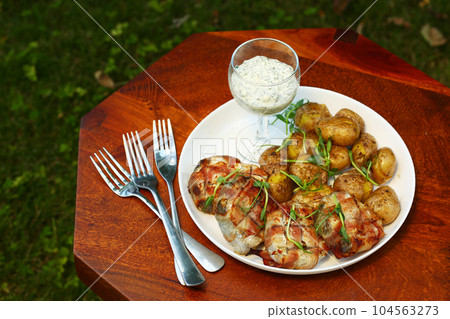 heck fish steaks roasted in bacon ham roll with new jacket potatoes and green arugula closeup photo heck fish steaks roasted in bacon ham roll with new jacket potatoes and green arugula closeup photo 104563273