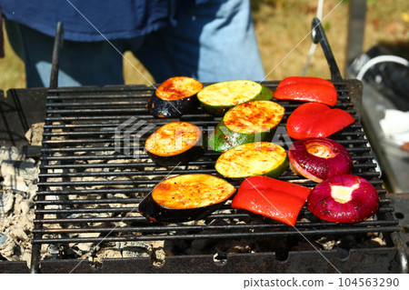 cooking vegetables zucchini, red onion, paprika and eggplant on grill bar closeup photo 104563290