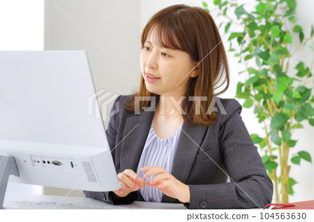 一個在辦公桌前努力工作的年輕女子 一個在辦公桌前努力工作的年輕女子 104563630