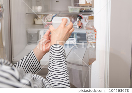 [一位家庭主婦從冰箱裡拿出一個水龍頭] 104563678
