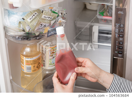 [Housewife taking out ketchup from the refrigerator] 104563684