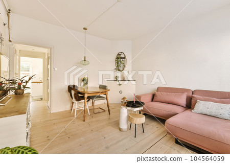 a living room with a pink couch and some plants on the table in front of the couch is an open door 104564059