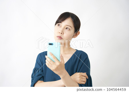 Middle-aged woman holding a smartphone and thinking White background 104564459