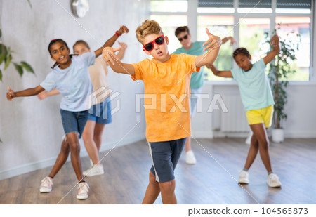 Boy in sun glasses perform choreographic exercise and teach social dance Jazz-modern with friends Boy in sun glasses perform choreographic exercise and teach social dance Jazz-modern with friends 104565873