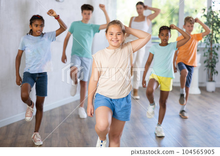 Cheerful preteen girl enjoying active dancing during group training 104565905