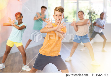 Boy perform choreographic exercises and teach energetic social dance waacking with friends Boy perform choreographic exercises and teach energetic social dance waacking with friends 104565914