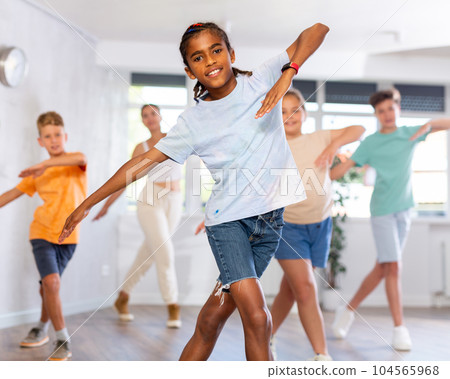 Boy exercising in group of classmates during dance class at school Boy exercising in group of classmates during dance class at school 104565968