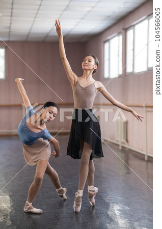Two Asian ballerinas are dancing in the class.  104566005
