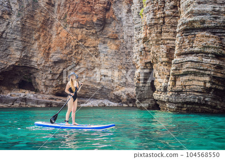 Young women Having Fun Stand Up Paddling in blue water seaamong the rocks in Montenegro. SUP 104568550