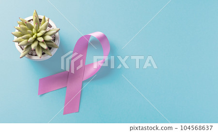 Pink awareness ribbon on blue background, top view with copy space 104568637