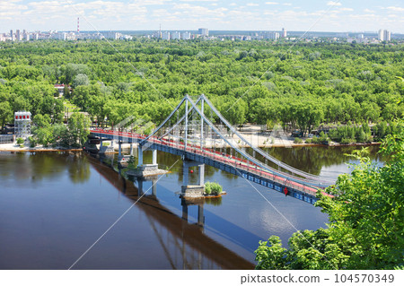 Summer landscape, view of the pedestrian bridge over the Dnipro river in Kyiv and Trukhanov island on a sunny afternoon. Summer landscape, view of the pedestrian bridge over the Dnipro river in Kyiv and Trukhanov island on a sunny afternoon. 104570349