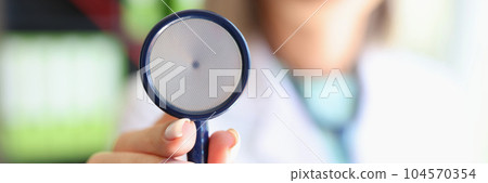 Woman doctor posing in clinic office and showing stethoscope 104570354