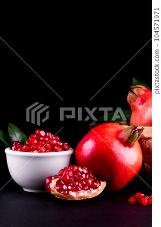 Ripe pomegranate fruits on the wooden background Ripe pomegranate fruits on the wooden background 104571971