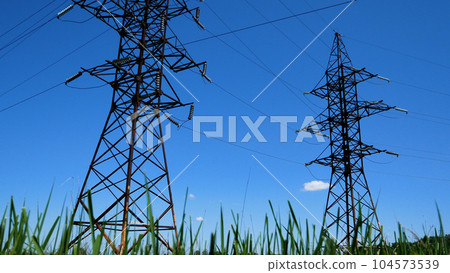 Towers of high-voltage power lines against the blue sky. Panorama, bottom view 104573539