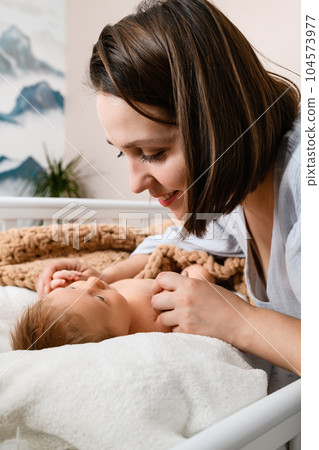 Smiling mom hold hands of newborn baby 104573977