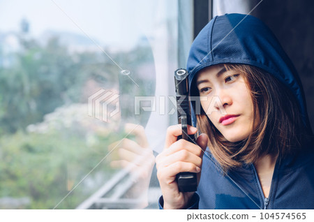 Female criminal (or thief) wearing hood and looking thought window for waiting her victim. 104574565