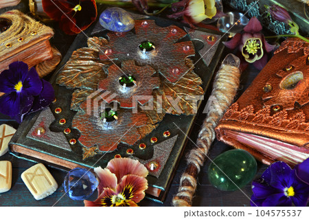 Still life with magic book of spells, runes and wand on witch table. Occult, esoteric and witchcraft concept. Mystic background with vintage objects Still life with magic book of spells, runes and wand on witch table. Occult, esoteric and witchcraft concept. Mystic background with vintage objects 104575537
