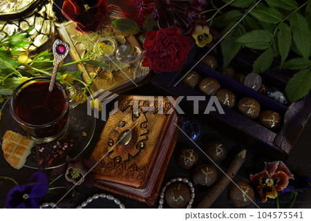 Still life with magic book of spells, runes and cup on witch ritual table. Occult, esoteric and witchcraft concept. Mystic background with vintage objects Still life with magic book of spells, runes and cup on witch ritual table. Occult, esoteric and witchcraft concept. Mystic background with vintage objects 104575541