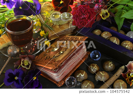 Still life with flowers, magic book of spells, cups on witch ritual table. Occult, esoteric and witchcraft concept. Mystic background with vintage objects Still life with flowers, magic book of spells, cups on witch ritual table. Occult, esoteric and witchcraft concept. Mystic background with vintage objects 104575542