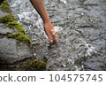 Woman's hand touching river water 104575745