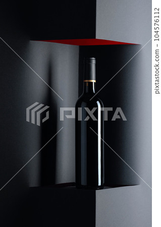 Unopened bottle of red wine on a black background. Copy space. 104576112