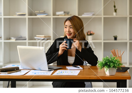 Attractive businesswoman drinking coffee and looking away through the window Attractive businesswoman drinking coffee and looking away through the window 104577236