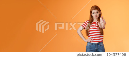 Time to stop. Serious-looking displeased bossy confident redhead girl extend arm in prohitibion, forbidden gesture, smirk disbelief and doubtful, warn not trespass, stand orange background 104577406