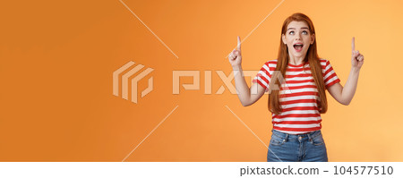 Surprised excited cheerful ginger girl see amazing opportunity, look pointing up amused, drop jaw gasping astonished, pleased awesome cool advertisement, reacting thrilled top copy space Surprised excited cheerful ginger girl see amazing opportunity, look pointing up amused, drop jaw gasping astonished, pleased awesome cool advertisement, reacting thrilled top copy space 104577510
