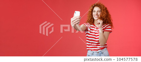Sassy good-looking stylish charismatic redhead female curly hairstyle winking cheeky expression making flirty kinky faces hold smartphone taking selfie record video message play funny facial filters 104577578