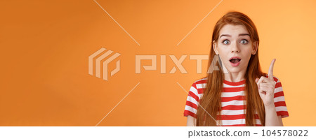 Got idea. Excited redhead woman sharing interesting plan, raise index finger eureka gesture, open mouth say thought, remember important thing, stare camera stunned, finally understand 104578022