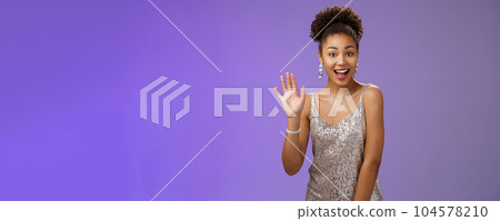 Friendly charming outgoing african-american woman see friend part nightclub smiling broadly say hi waving hello gesture greeting welcoming sociable, glad meet, standing joyful blue background 104578210