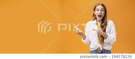 Waist-up shot of excited speechless impressed young cute woman with curly hair dropping jaw from amazement pointing left thrilled telling about awesome copy space at camera astonished Waist-up shot of excited speechless impressed young cute woman with curly hair dropping jaw from amazement pointing left thrilled telling about awesome copy space at camera astonished 104578226