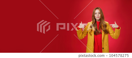 Self-assured assertive and optimsitic charming female entrepreneur with ginger hair in yellow coat pointing at herself proudly brag own success or willing to be candidate smiling confident 104578275