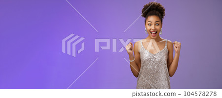 Impressed surprised thrilled joyful charming elegant african-american woman winning money casino achieve success yelling happily raise fists victory triumph gesture cheering gladly blue background 104578278