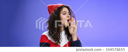 Portrait of worried sister calling sibling outdoors open mouth looking left seriously and holding palm near lips as shouting name searching someone, posing concerned over blue background Portrait of worried sister calling sibling outdoors open mouth looking left seriously and holding palm near lips as shouting name searching someone, posing concerned over blue background 104578655