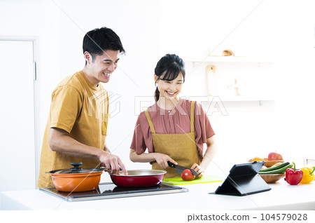 年輕夫婦一邊做飯一邊看著平板電腦 104579028