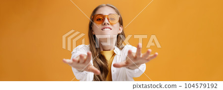 Girl reaching with desire at camera wanting grab it. Portrait of good-looking stylish caucasian young woman in trendy sunglasses biting lip from will to have something pulling hands towards 104579192