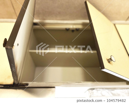 In an empty hanging cupboard in an old kitchen 104579482