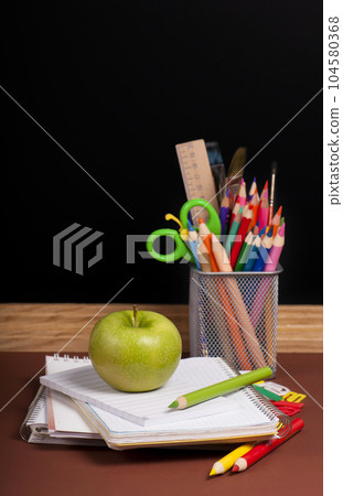 Magnifying glass, scissors, colored paper, textbooksboard, books, pencils, opened empty notebook against a dark background Magnifying glass, scissors, colored paper, textbooksboard, books, pencils, opened empty notebook against a dark background 104580368